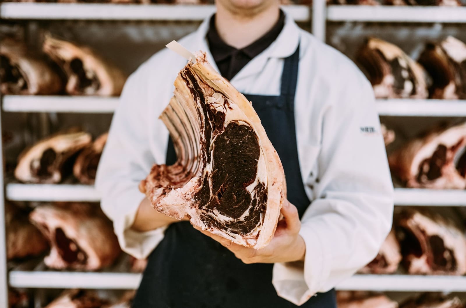 Butchery preparation behind the counter at Neil Powell, Flannel Street, with the bench in view through the window of the shop.